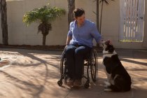 Инвалид ласкает собаку на заднем дворе в солнечный день — стоковое фото