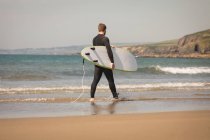 Vista traseira do surfista com prancha de surf andando na praia — Fotografia de Stock