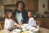 Großmutter steht mit ihren Enkelinnen zu Hause in der Küche — Stockfoto