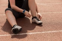 Low section of female athletic tying shoe laces on a running track — Stock Photo