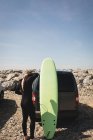 Vista posteriore del surfista che indossa una muta vicino alla spiaggia — Foto stock