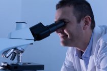 Мужчина-ученый, использующий микроскоп в лаборатории — стоковое фото