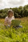 Jovem mulher usando laptop no campo — Fotografia de Stock