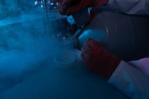 Hombre científico vertiendo líquido en un tazón en el laboratorio - foto de stock