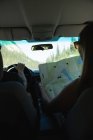 Вид ззаду пари, дивлячись на карту під час подорожі в машині — стокове фото