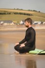 Surfista seduto sulla tavola da surf in spiaggia in una giornata di sole — Foto stock