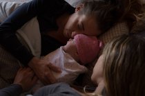 Nahaufnahme von lesbischem Paar mit Baby, das es sich zu Hause auf dem Bett gemütlich macht — Stockfoto