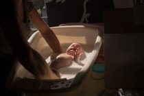 Mãe tomando banho seu bebê na banheira em casa — Fotografia de Stock