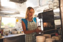 Bellissimo cameriere femminile preparare il caffè in camion cibo — Foto stock