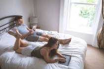 Пара с помощью ноутбука и цифрового планшета в спальне дома — стоковое фото