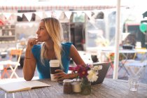 Задумчивая женщина пьет кофе в кафе на открытом воздухе — стоковое фото