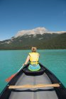 Rear view of woman boating in river in mountains — Stock Photo