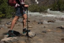 Low section of female hiker crossing the stream at countryside — Stock Photo