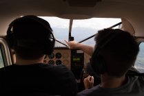 Пилоты разговаривают друг с другом во время полета в кабине самолета — стоковое фото