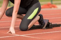 Low section of female athlete ready to run on running track — Stock Photo