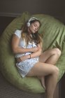 Женщина слушает музыку в наушниках, пока спит дома — стоковое фото