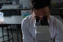 Científico masculino usando microscopio en laboratorio - foto de stock