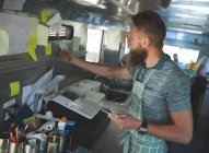 Camarero mirando pedidos en nota adhesiva en camión de comida - foto de stock