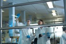 Equipo de científicos discutiendo sobre tablero de vidrio en laboratorio - foto de stock