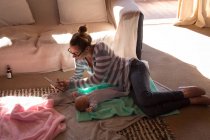 Мати з дитиною використовує цифровий планшет на підлозі вдома — стокове фото
