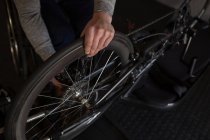 Sección media del hombre discapacitado reparando silla de ruedas en el taller - foto de stock