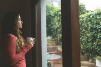 Femme réfléchie prenant un café à la maison — Photo de stock