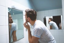 Young man looking in the mirror at home — Stock Photo