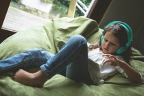 Menina ouvir música ao usar tablet digital em casa — Fotografia de Stock