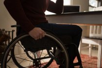 Sección media del hombre discapacitado en silla de ruedas en casa - foto de stock