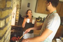 Casal interagindo uns com os outros na cozinha em casa — Fotografia de Stock