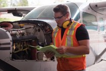 Mechaniker liest Dokumente im Flugzeughangar — Stockfoto