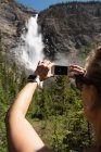 Mujer haciendo clic en fotos con teléfono móvil en las montañas - foto de stock