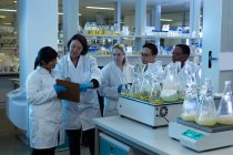 Equipe de cientista interagindo sobre prancheta em laboratório — Fotografia de Stock