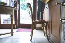 Section basse de fille debout sur la chaise dans la cuisine à la maison — Photo de stock