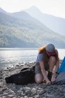 Mann baut Zelt am Flussufer in Bergen auf — Stockfoto
