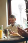 Старший чоловік, використовуючи цифровий планшетний в будинку маючи сніданок — стокове фото