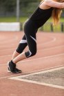 Vue latérale de l'exercice athlétique féminin sur piste de course — Photo de stock
