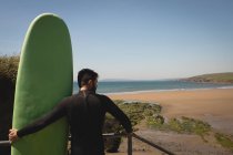 Vista posteriore del surfista con tavola da surf in piedi sulle scale — Foto stock