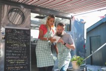 Young couple using digital tablet in food truck — Stock Photo
