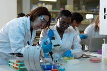 Женщины-ученые используют пипетку вместе в лаборатории — стоковое фото