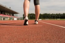 Sección baja de pie atlético femenino en pista de atletismo - foto de stock