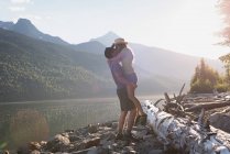 Couple kissing each other near riverside in mountains — Stock Photo