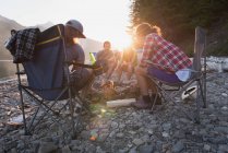 Group of friends roasting hot dogs on campfire in mountains — Stock Photo