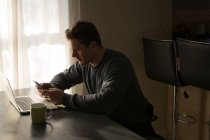 Mann benutzte Handy zu Hause auf Esstisch — Stockfoto