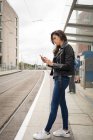 Mujer usando el teléfono móvil en la plataforma en la estación de tren - foto de stock