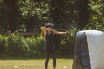 Mulher praticando tiro com arco no campo de treinamento em um dia ensolarado — Fotografia de Stock