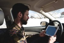 Homem usando tablet digital no carro durante o inverno — Fotografia de Stock