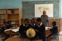 Crianças em idade escolar usando globo em sala de aula na escola — Fotografia de Stock