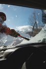 Uomo pulizia neve dal parabrezza auto durante l'inverno — Foto stock