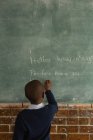 Estudante escrevendo em quadro-negro em sala de aula na escola — Fotografia de Stock